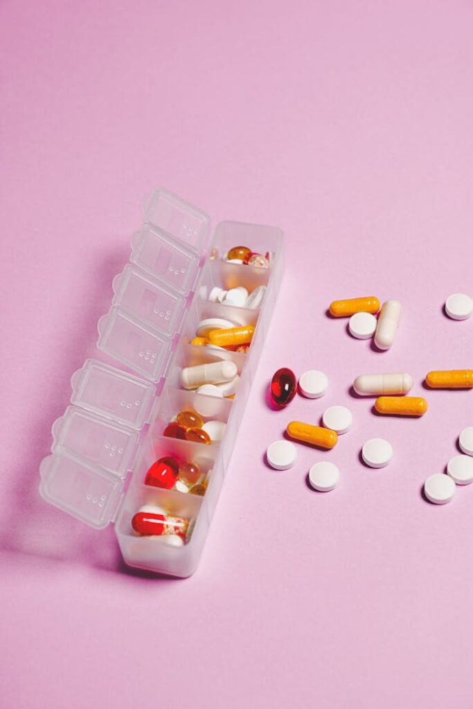 pexels photo 3683042 Colorful assortment of pills and capsules in organizer on pink backdrop.